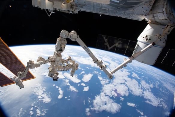 The Canadarm2 and DEXTRE alongside a docked Dragon capsule on the ISS, 2019